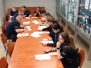 przy długim stole siedzą policjanci na