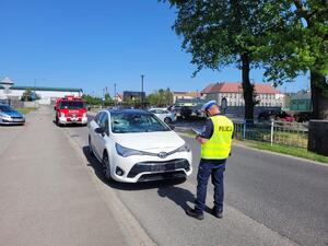 samochód osobowy z uszkodzoną szybą oraz zderzakiem policjant w kamizelce odblaskowej