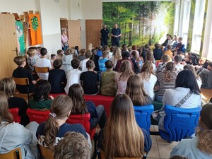 dwóch policjantów stojących na korytarzu przed nimi siedząca młodzież