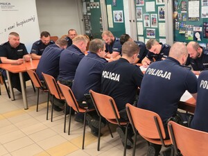 policjanci siedzą na krzesłach wokół stoły