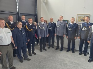 przy ścianie stoją nieumundurowani ludzie wśród nich widoczni są również umundurowani policjanci i wojskowi i straż graniczna