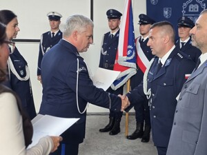 umundurowany policjant wręcza akt nominacji na wyższy stopień  umundurowanemu policjantowi