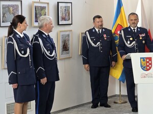 trzech umundurowanych policjantów i jedna policjantka jeden z policjantów stoi za mównicą