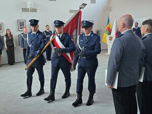 trzech policjantów jeden z nich niesie sztandar