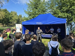 namiot policjant w umundurowaniu młodzież w tle widoczne jezioro