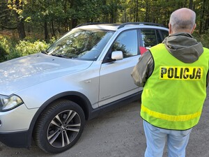 policjant w kamizelce pisze protokół przed nim osobowe auto